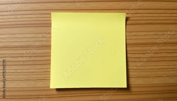 Fototapeta Blank yellow sticky note on a wooden surface.