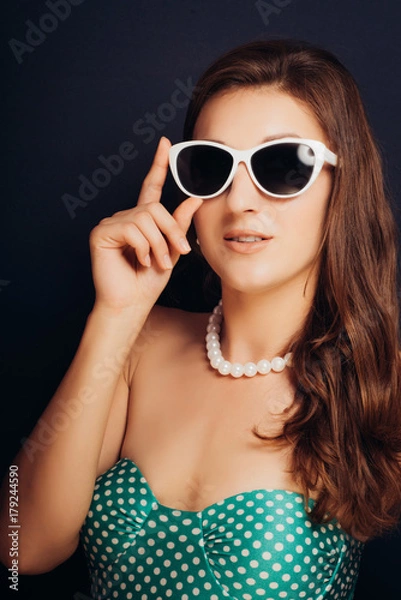 Fototapeta Woman on a dark background close-up in a swimsuit and wearing glasses. Pin-up style