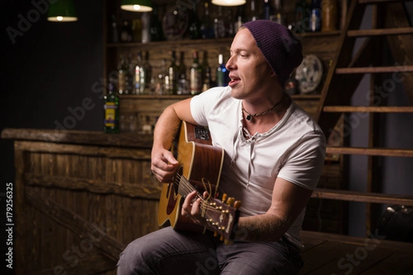 Obraz man in white shirt with guitar singing song in bar