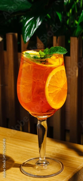 Fototapeta Refreshing fruity drink served in a tall glass with mint and orange