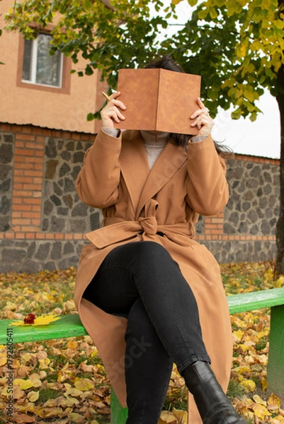 Fototapeta Woman covering her face with a notebook