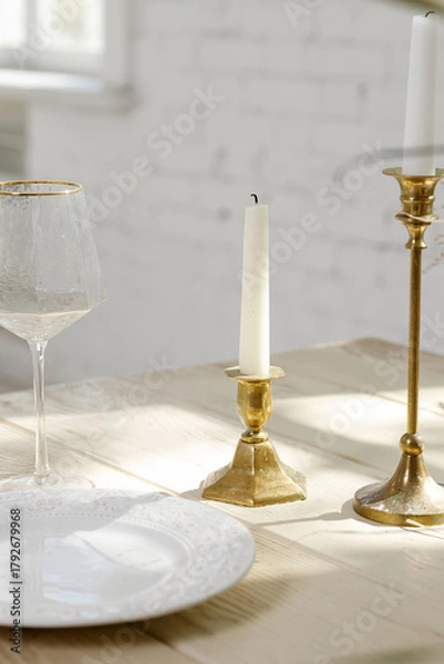 Obraz Elegant table setting with candle holders, white plate, and wine glass in natural sunlight