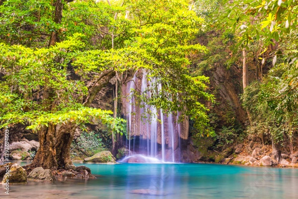 Obraz Beautiful waterfall in tropical jungle forest with big green tree and emerald lake on foreground. Nature landscape of Erawan National park, Kanchanaburi, Thailand