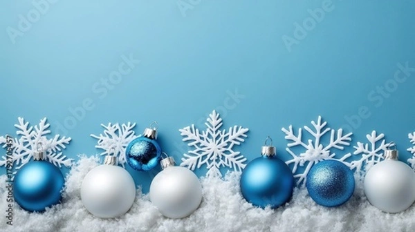 Fototapeta A festive arrangement of blue and white Christmas ornaments and snowflakes against a light blue background, evoking a cheerful winter atmosphere.