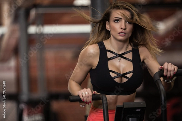 Obraz Dziewczyna jadąca na rowerku na siłowni