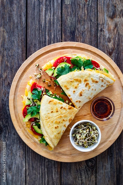 Fototapeta Healthy breakfast - italian piada wraps with scrambled eggs, tomatoes, avocado, coriander and bean sprouts. Top view