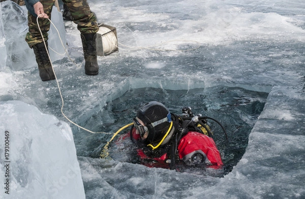 Fototapeta diver plunges into the hole in the ice of lake Baikal