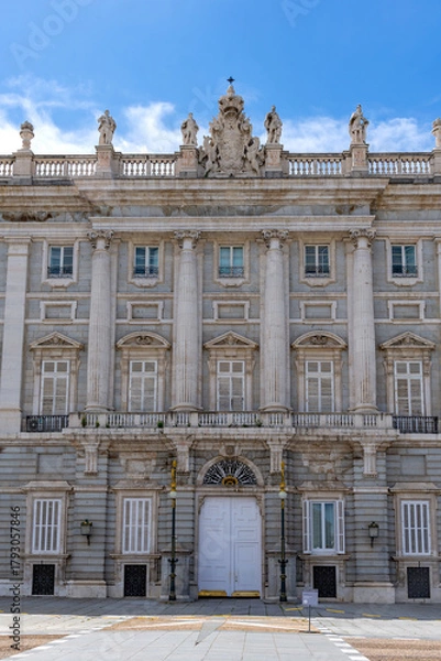 Obraz A detailed view of the Palacio Real's central entrance pavilion, featuring twin columns, a grand white doorway, ornate sculpture work, and the royal coat of arms at the rooftop.