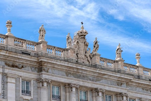 Obraz Close-up upward view of the Palacio Real’s ornate gray and white neoclassical façade, showing columns, statues, balustrade, and detailed windows against the sky