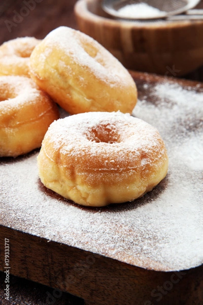 Fototapeta powdered sugar donuts on rustic brown table.