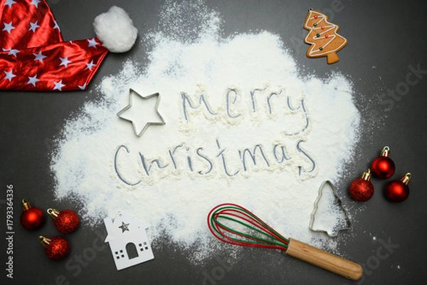 Fototapeta Top view of Christmas baking background with flour text, gingerbread shapes, rolling pin and red baubles. Great for greeting cards, culinary ads and festive visual design.