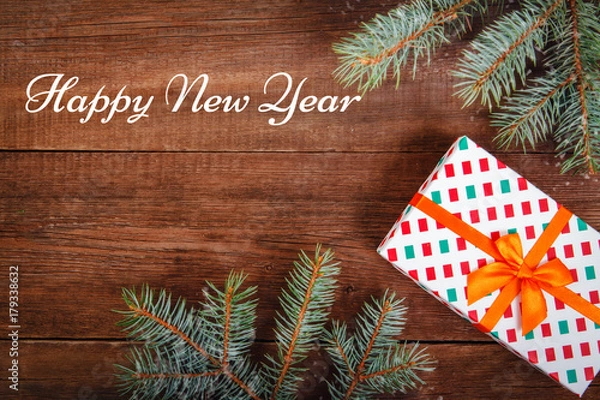 Fototapeta Christmas composition. Fir branches and a gift on a brown background. Space for text, top view. Background