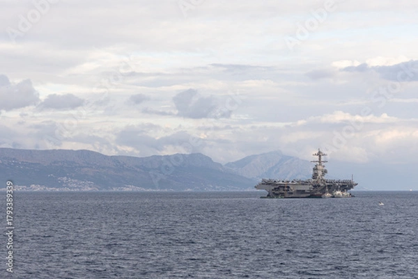 Obraz Aircraft Carrier on Open Sea Near Distant Mountain Range Under a Cloudy Sky