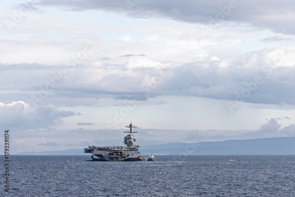 Obraz Naval Aircraft Carrier At Sea With Small Support Vessel Under Cloudy Sky