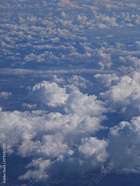 Obraz Majestic clouds seen from an airplane window during a clear day over the landscape below