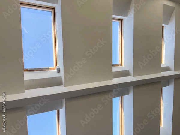 Fototapeta Multiple skylight windows installed in a contemporary sloped ceiling, showcasing modern interior architecture, natural light design, and bright attic space for residential and commercial concepts