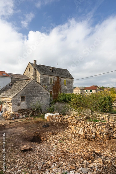 Fototapeta Rustic Stone Building With Green Shutters Overlooking Garden And Clear Blue Sky, Grohote, Solta