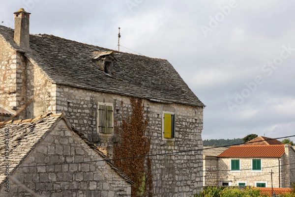 Obraz Rustic Stone Building With Green Shutters Overlooking Garden And Clear Blue Sky, Grohote, Solta