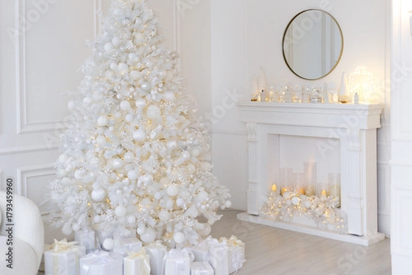 Obraz White Christmas interior with decorated tree, glowing garlands, candles, white gifts, elegant festive decor, and a round mirror above a white fireplace.