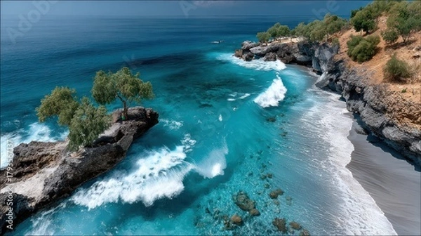 Fototapeta Aerial view of a turquoise ocean meeting a rocky coast with beach and trees