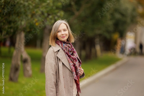 Obraz Warm autumn day in the park with a smiling woman wearing a scarf
