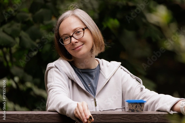 Fototapeta Smiling woman enjoying a quiet moment in a lush garden during the peaceful afternoon hours