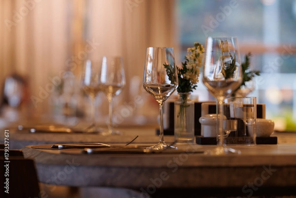 Fototapeta Elegant dining setting with wine glasses and flowers near a window in a cozy restaurant