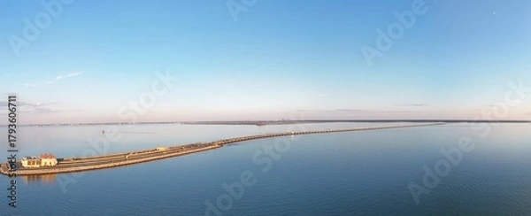 Fototapeta Aerial View Of Long Monitor Merrimac Memorial Bridge Tunnel crossing tranquil blue water of Hampton Roads Channel with a distant harbor and open sky