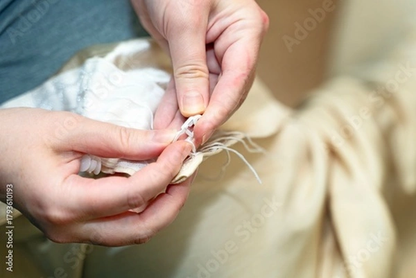 Fototapeta Female hands inserting plastic curtain hooks after washing for rod attachment