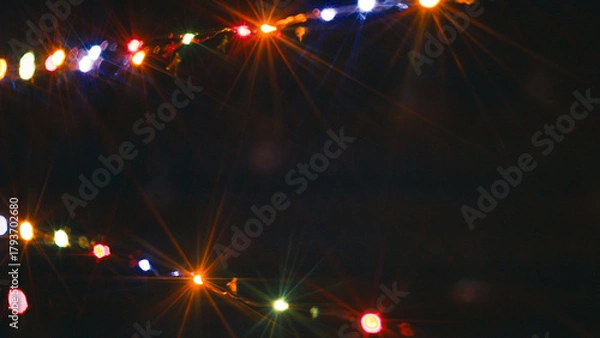 Fototapeta String of Christmas lights flashing at night with copy space in the center