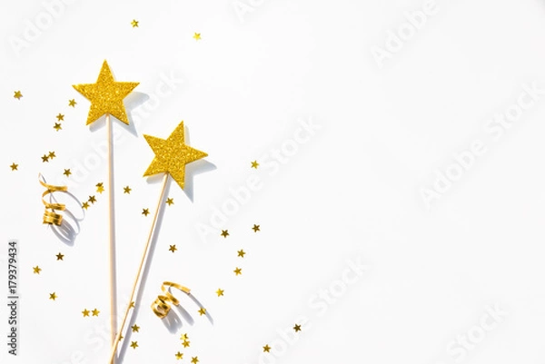 Fototapeta Two golden party magic wands, sequins and ribbons on a white background. Copy space.