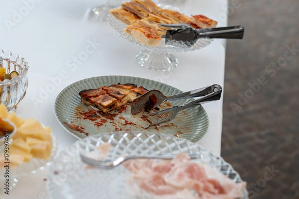Fototapeta Delicious party food selection arranged on elegant serving dishes with tongs ready for guests to serve themselves at an indoor event