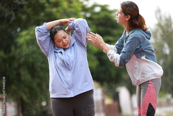 Obraz Two slim and plus size woman with sport jacket together stretch warm-up exercise on an outdoor running track, wellness and healthy lifestyle