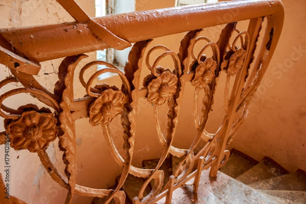 Fototapeta Detailed close-up of an old, ornate metal banister with peeling paint and cobwebs, part of a decaying staircase in a forgotten early 20th-century mansion