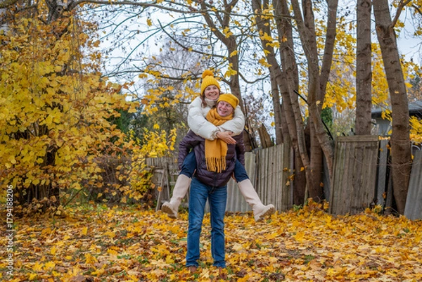 Fototapeta Midlife couple enjoying autumn day outdoors, surrounded by colorful fall leaves, sharing laughter and joy, creating lasting memories in a serene natural setting