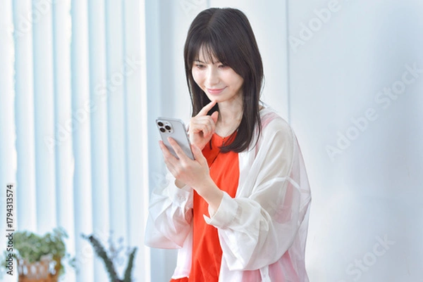 Obraz 部屋でスマホを見る若い女性