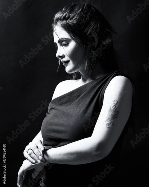 Obraz High-quality monochrome portrait of an elegant woman in a one-shoulder black dress, posing gracefully in studio lighting. Perfect for fashion, beauty, and artistic emotion concepts.
