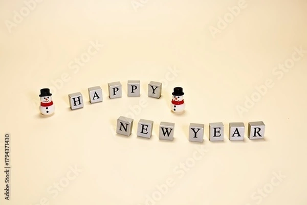 Fototapeta Charming snowman figurines and blocks spell happy new year on a soft background