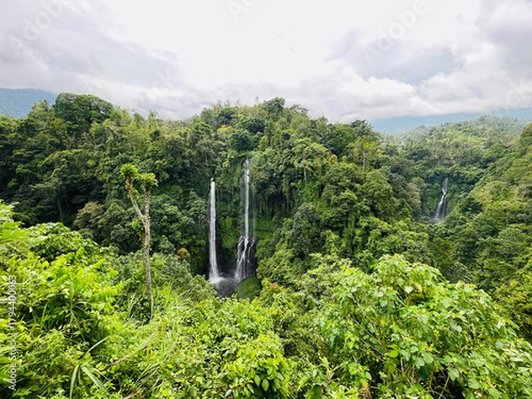 Obraz Scenic aerial view of Sekumpul Waterfall from Sudaji village in Bali, Indonesia — lush tropical rainforest, cascading twin falls, and vibrant green landscape.