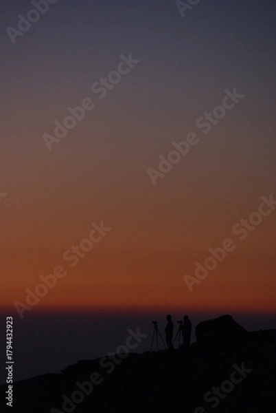 Fototapeta Silhouettes of photographers waiting to see the sunrise on the mountaintop in the early morning, and a sunrise scene (hyper zoom shot) / 早朝の山頂で御来光の瞬間を待つカメラマンたちのシルエットと朝焼けシーン(冬の朝，超望遠ズーム撮影)