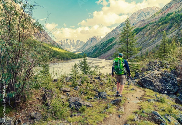Fototapeta A hiker walking through a scenic mountain landscape. Backpacking is a way to immerse yourself in nature, exploring remote areas and enjoying breathtaking scenery.
