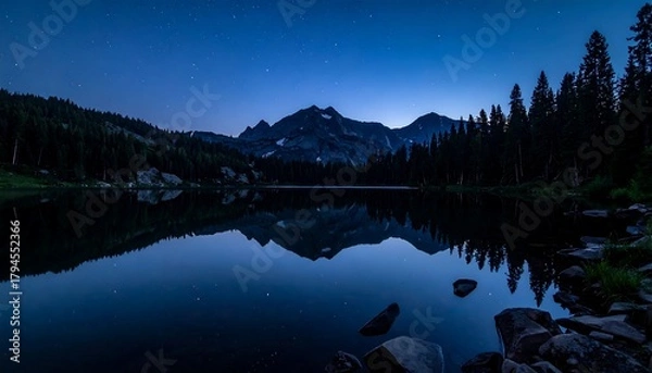 Obraz Starry sky over a mountain lake reflecting jagged peaks and silhouetted evergreens on a tranquil, dark water surface