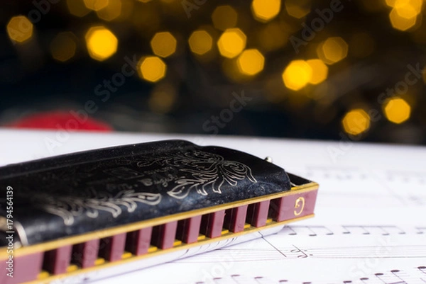 Fototapeta harmonica, music book on a blurred background with highlights. bokeh, close-up.
