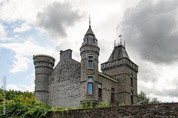 Fototapeta Imposing towers and intricate stonework of Spontin Castle rise beneath dramatic clouds, showcasing the architectural grandeur and historical essence of one of Belgium’s most enchanting medieval castle