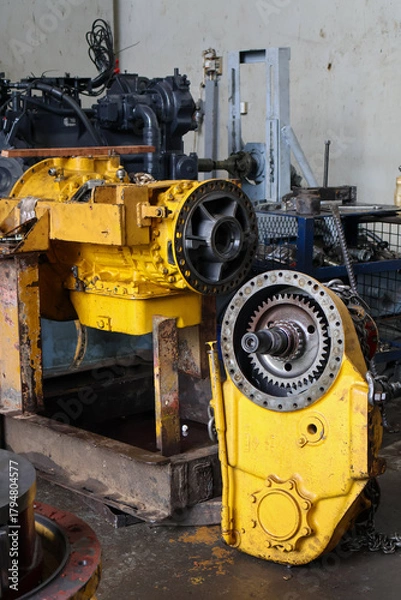 Fototapeta Heavy-duty allison transmission assembly and final drive unit disassembled for maintenance in a professional industrial workshop setting.