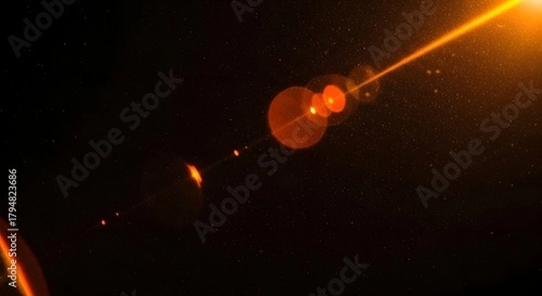 Fototapeta Abstract glowing orange lens flare effect with small particles and starlike dots on a dark background, representing light and energy in space