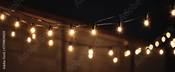 Fototapeta The String Lights Casting Warm Bokeh Glow Over a Cozy Outdoor Evening Setting
