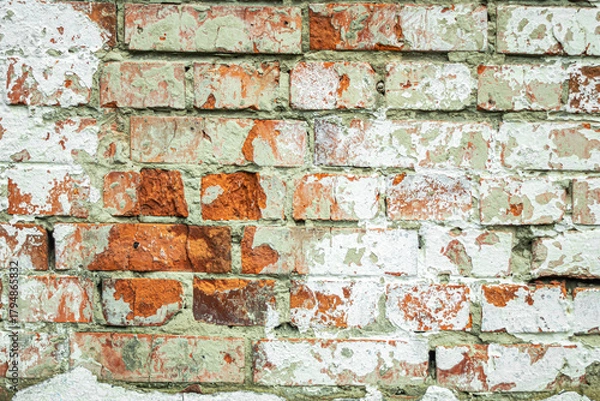 Fototapeta A dilapidated old red brick wall painted white as an abstract background.