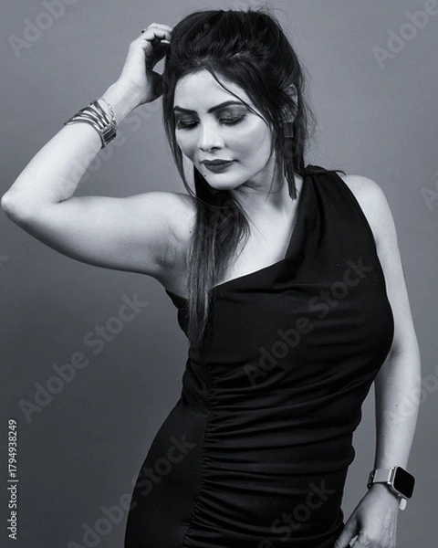 Obraz Monochrome portrait of a confident woman in a black one-shoulder dress, posing gracefully with a soft expression. Perfect for fashion, beauty, and lifestyle themes representing elegance and confidence