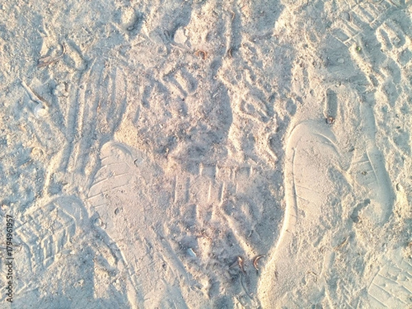 Fototapeta Shoe Footprints and Textured Marks on Soft Sandy Ground Creating Natural Outdoor Pattern Background Scene